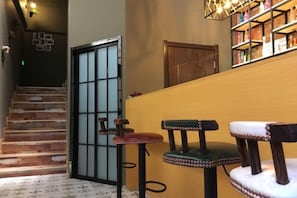 A staircase leading to a room with a wooden door, a bar area with stools, and a bookshelf. - Pian an Yi Yu (Chizhou)