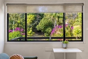 A room with a large window overlooking a garden with various plants and flowers.