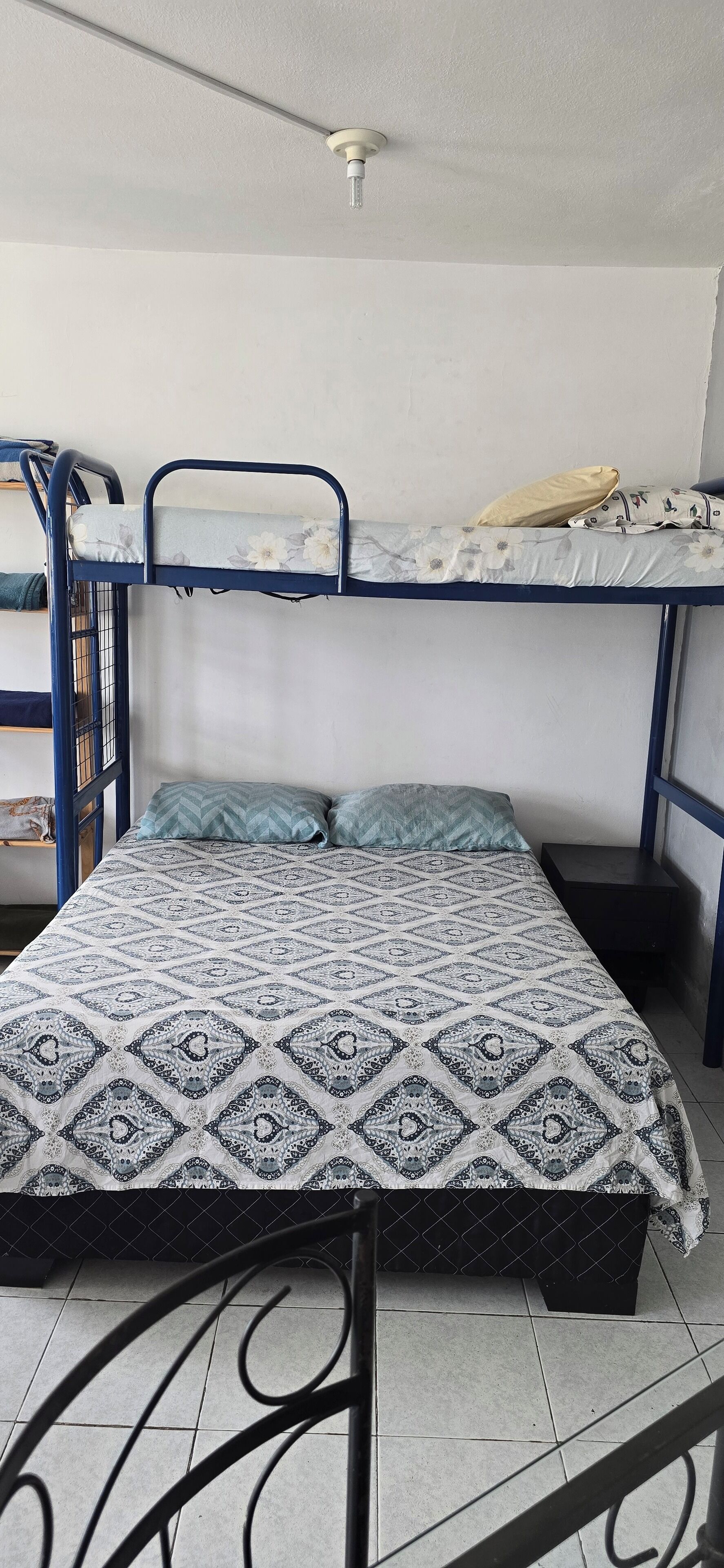 A bunk bed with a patterned bedspread, a ceiling fan, and a small bedside table.
