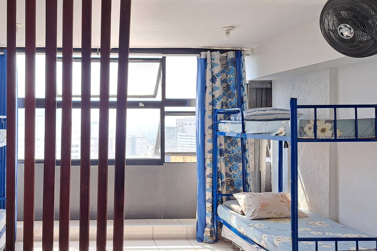 Un dormitorio con literas, una ventana y un ventilador.
