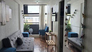 Un salon moderne avec un canapé gris, un fauteuil bleu et une petite table en bois.