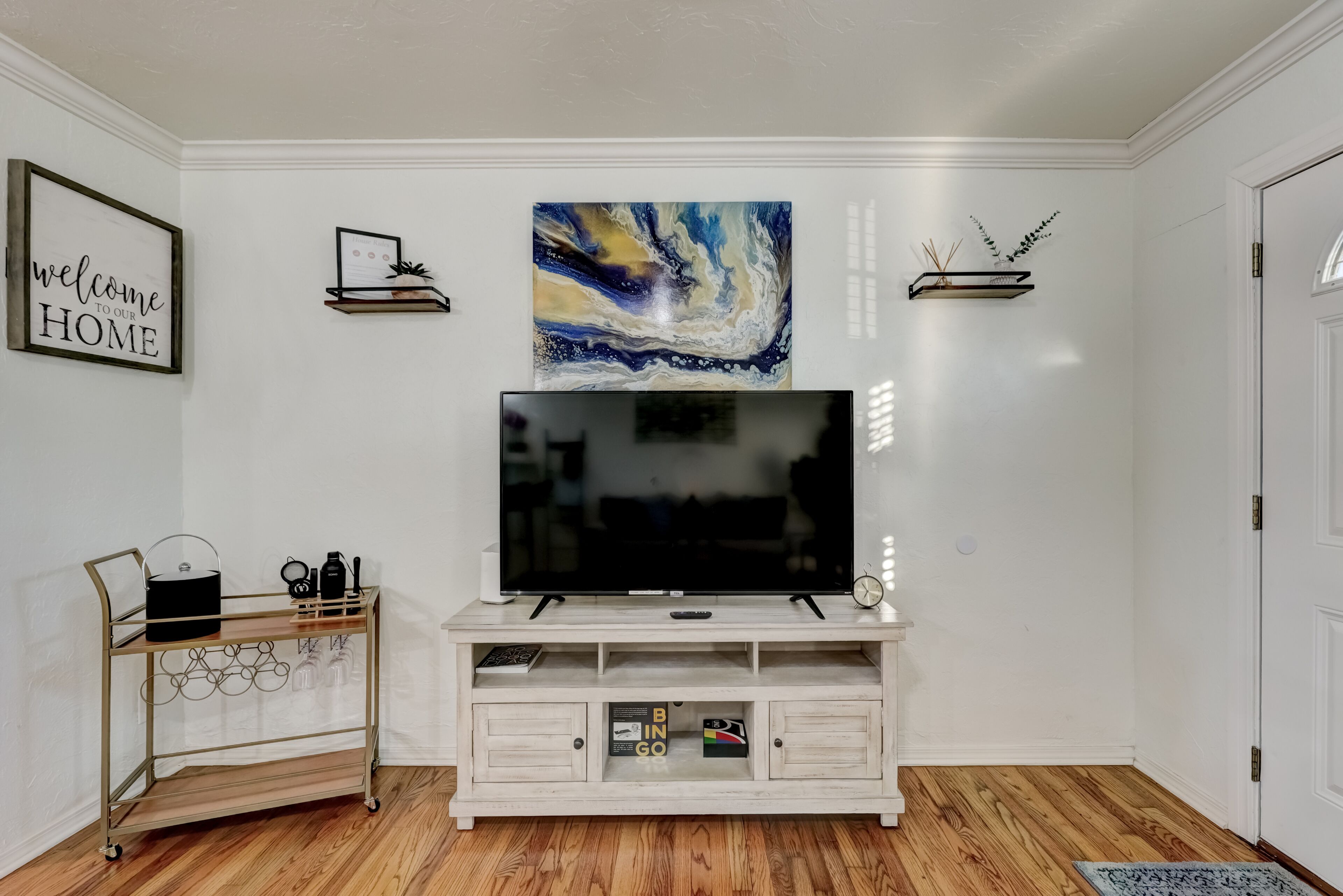 Ett vardagsrum med en TV placerad på en vit TV-möbel, ett soffbord och en bokhylla.