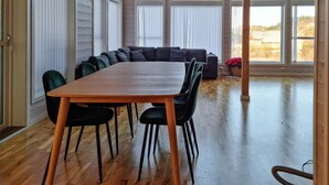 Ein Essbereich mit Holztisch und Stühlen, einer Couch und großen Fenstern.