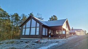 Eine Holzhütte mit großen Fenstern, einem geneigten Dach und einer Veranda.