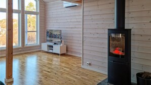 Ein Zimmer mit Holzwänden, einem Fernseher auf einem weißen Stand und einem Kaminofen.