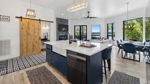Een moderne keuken met een groot schiereiland, een landelijke deur en uitzicht op de omgeving.