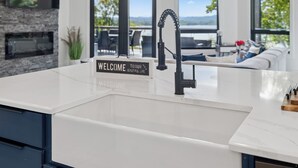 Een moderne keuken met een wit aanrecht, een zwarte kraan en een welkomstbord.