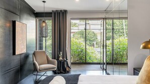 A modern bedroom with a large window, a chair, a bedside table, and a bed. - Urban Escape Glebe House (Glebe)