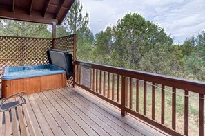 Une terrasse en bois avec un jacuzzi et un espace salon abrité.