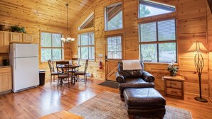 A wooden cabin interior with a kitchen, dining area, and seating space. - Cozy cabin for 2, private hot tub, King size bed! (Overgaard)