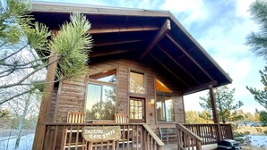 A wooden cabin with a porch, a bench, and a sign that reads "Tackling Rain 1748". - Cozy cabin for 2, private hot tub, King size bed! (Overgaard)