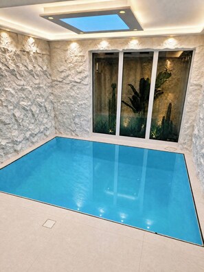 An indoor swimming pool with a stone wall and glass doors. - UG Neubau City Wohnung (optional Pool+Gym+2tes Bad extra buchbar) (Munich)