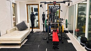 Une salle de sport à domicile équipée d’un banc de musculation, de supports pour les poids et d’un miroir.