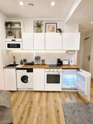 Una cocina moderna con electrodomésticos integrados, encimera de madera y alfombra gris.