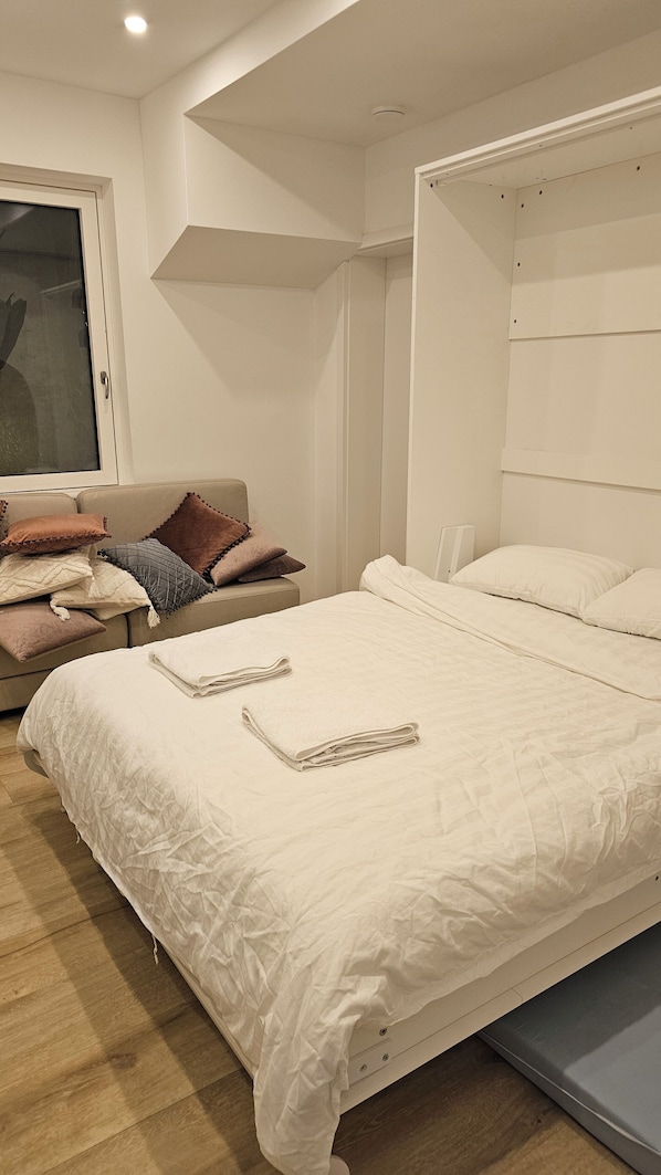 A bedroom with a large bed, a sofa, and a window. - UG Neubau City Wohnung (optional Pool+Gym+2tes Bad extra buchbar) (Munich)