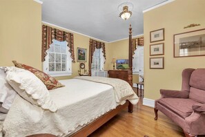 Un dormitorio con una cama grande, una silla de madera y un aparador.