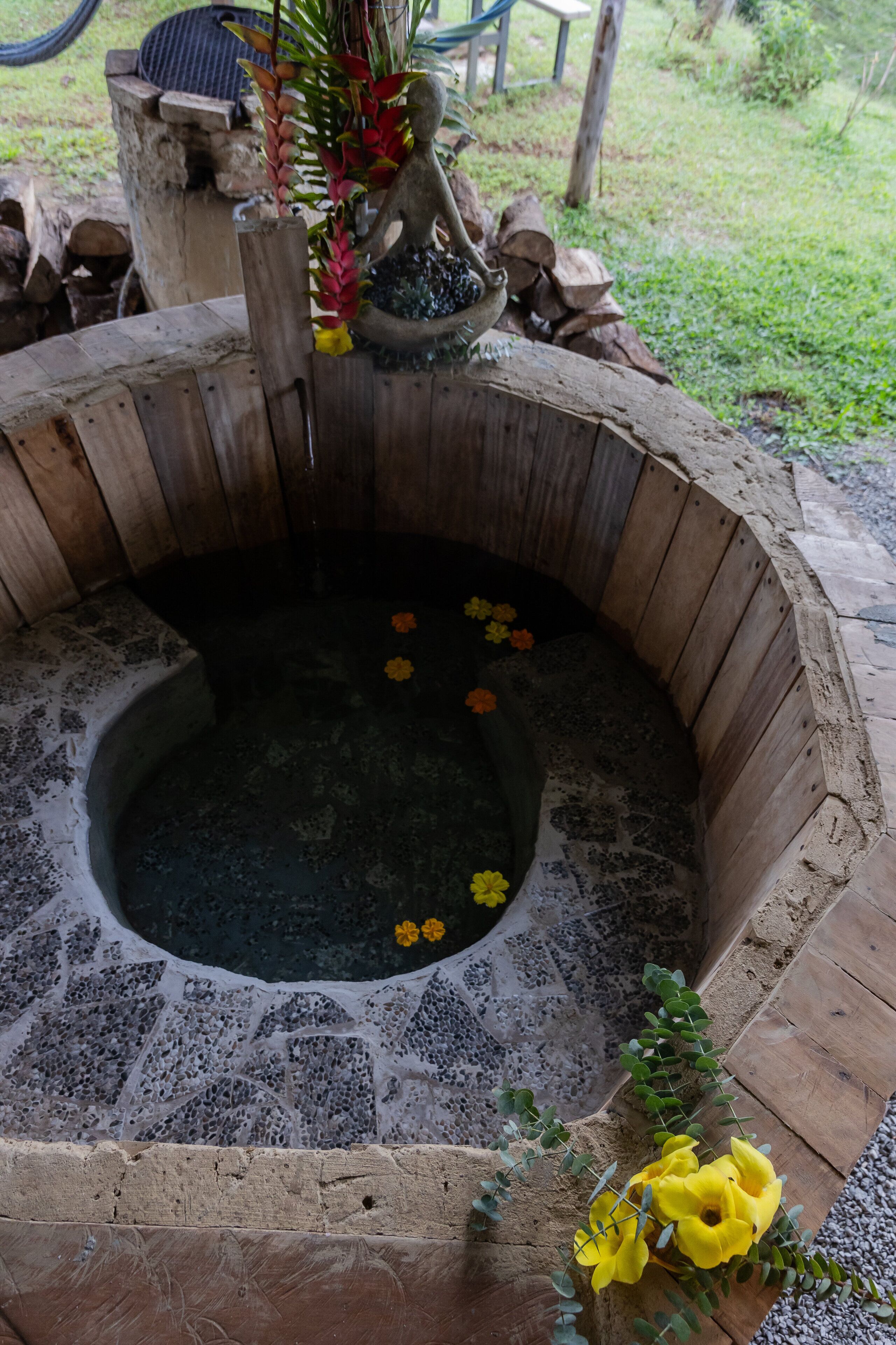 Un bain à remous en pierre, bordé de bois, entouré d’une terrasse en bois rustique.