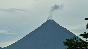 Una montaña con una columna de humo visible, rodeada por un cielo nublado.