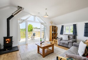 Een gezellige woonkamer met een open haard, een bank, een bijzettafeltje en een boekenkast.