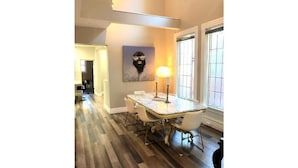 A dining area with a marble table and chairs, a painting on the wall, and a window with blinds.