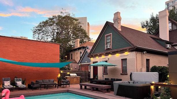 A backyard with a swimming pool, outdoor seating, and a barbecue area.