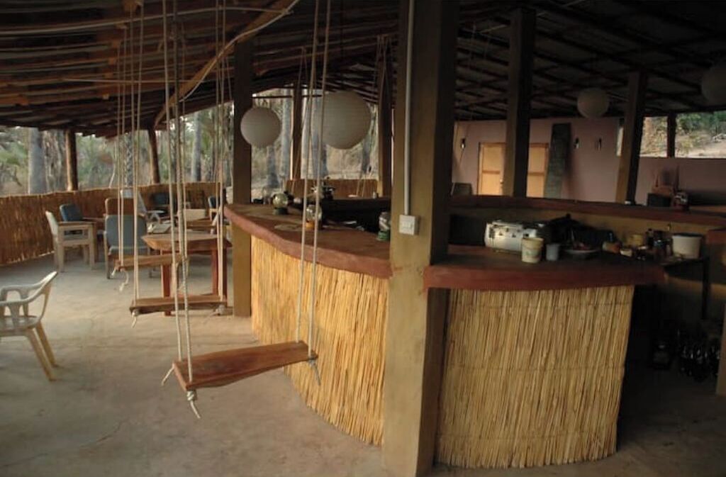 Un'area bar rustica con un bancone in paglia, sedie di legno e un design semplice e aperto.