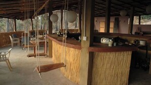 A rustic bar area with a thatched counter, wooden chairs, and a simple, open design. - Nemasu ecolodge: breathtaking!l (Gunjur)