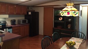 Una cocina compacta con muebles de madera, microondas y una mesa de comedor con sillas.