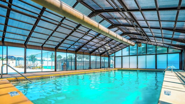 An indoor swimming pool with clear glass walls and a metal roof structure. - Pointe Royale, Step Free Entry, Indoor Pool (Branson)