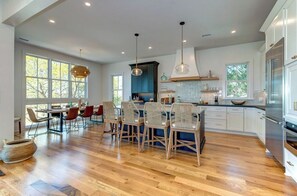 Una cocina amplia con suelo de madera, armarios blancos y una isla central con sillas.