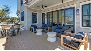 Une terrasse extérieure couverte, aménagée avec des meubles en osier, une table ronde et des ventilateurs de plafond.