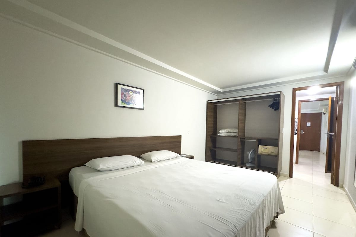 Une chambre à coucher comprenant un lit, une table de chevet, une armoire et un tableau encadré accroché au mur.