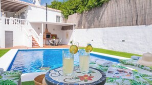 Ein Poolbereich mit Tisch, zwei Gläsern mit Getränken und einem Hut.