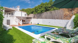 A swimming pool with a white deck, surrounded by a well-maintained lawn and a wooden fence. - Casa Maite Sol Nerja by Ruralidays (Málaga)