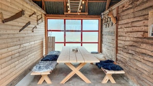 Eine rustikale Holzhütte mit einem großen Fenster, einem Holztisch mit Bänken und verschiedenen Jagdtrophäen an den Wänden.