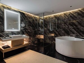 Ein modernes Badezimmer mit Marmorwand, einem großen Spiegel, einer Badewanne und einer Duschkabine aus Glas.