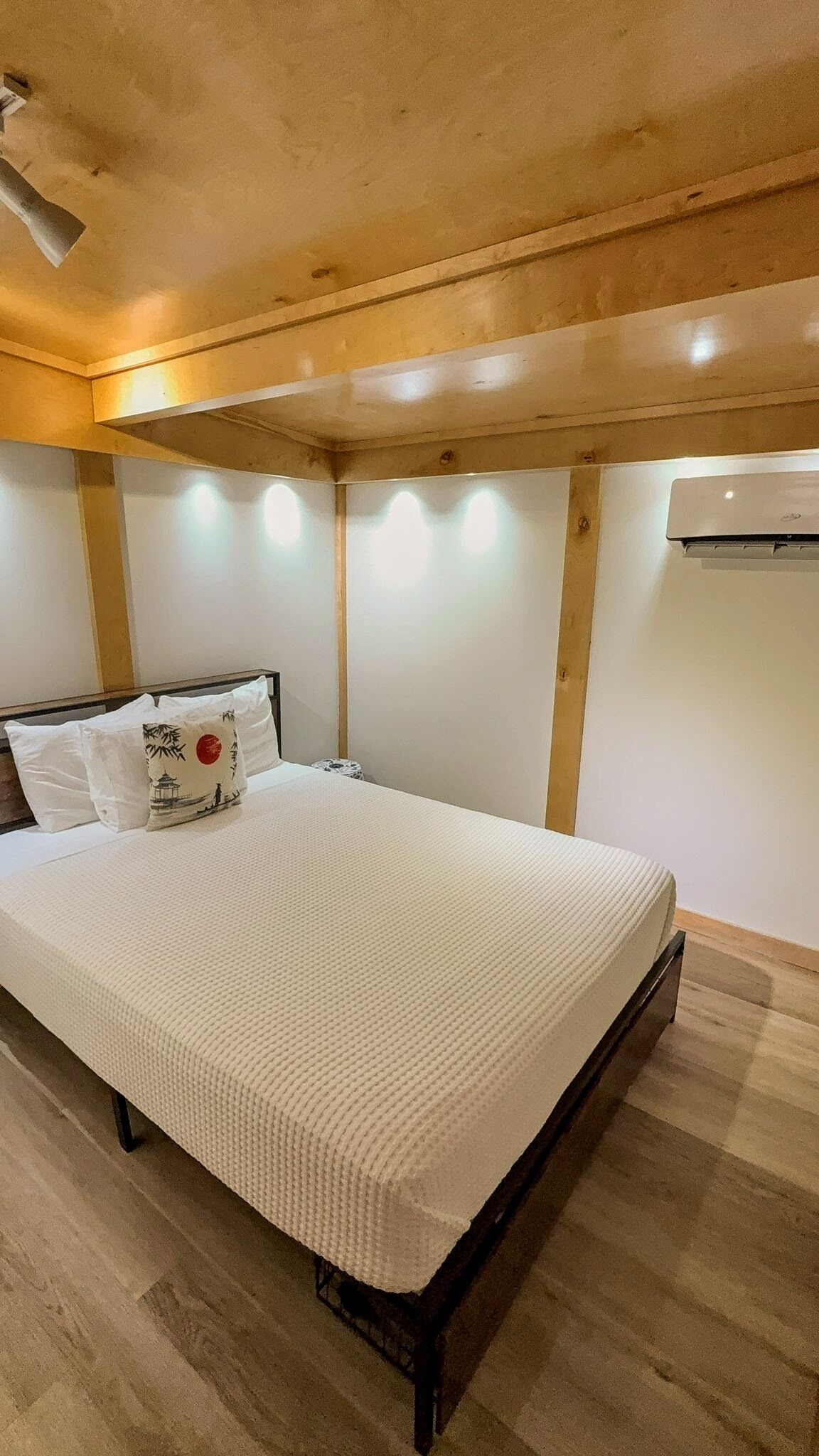 A neatly made bed with a white comforter and two pillows, one with a bamboo design.