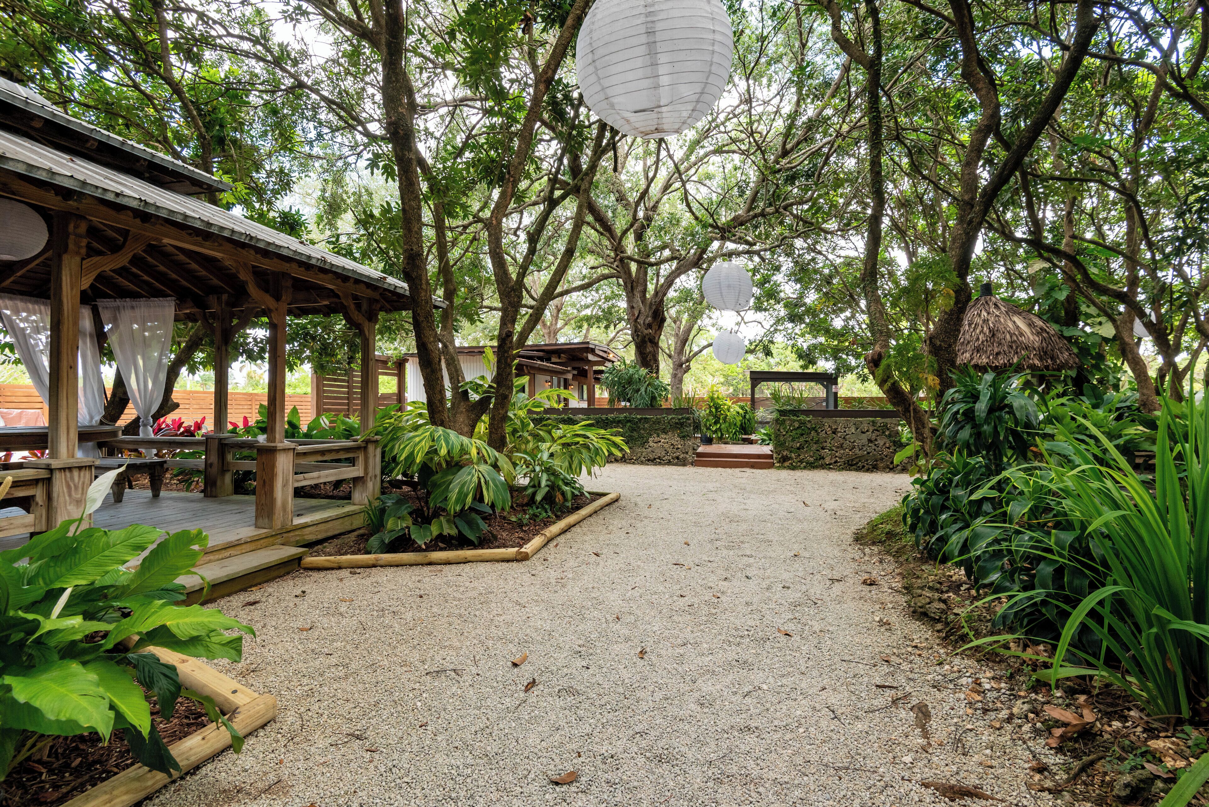 A covered outdoor area with a wooden deck, surrounded by lush greenery and trees.