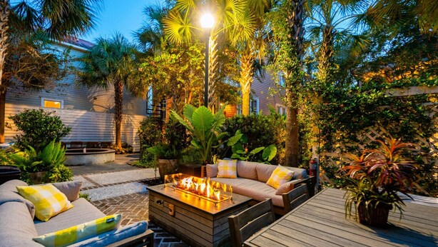 Eine Terrassengruppe mit Feuerstelle, Sitzgelegenheit und üppiger tropischer Bepflanzung.