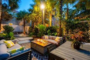 An outdoor patio with a fire pit, seating area, and lush tropical plants. - 6B at Saint Philip Square, One Block to King, Double Porch Oasis (Charleston)