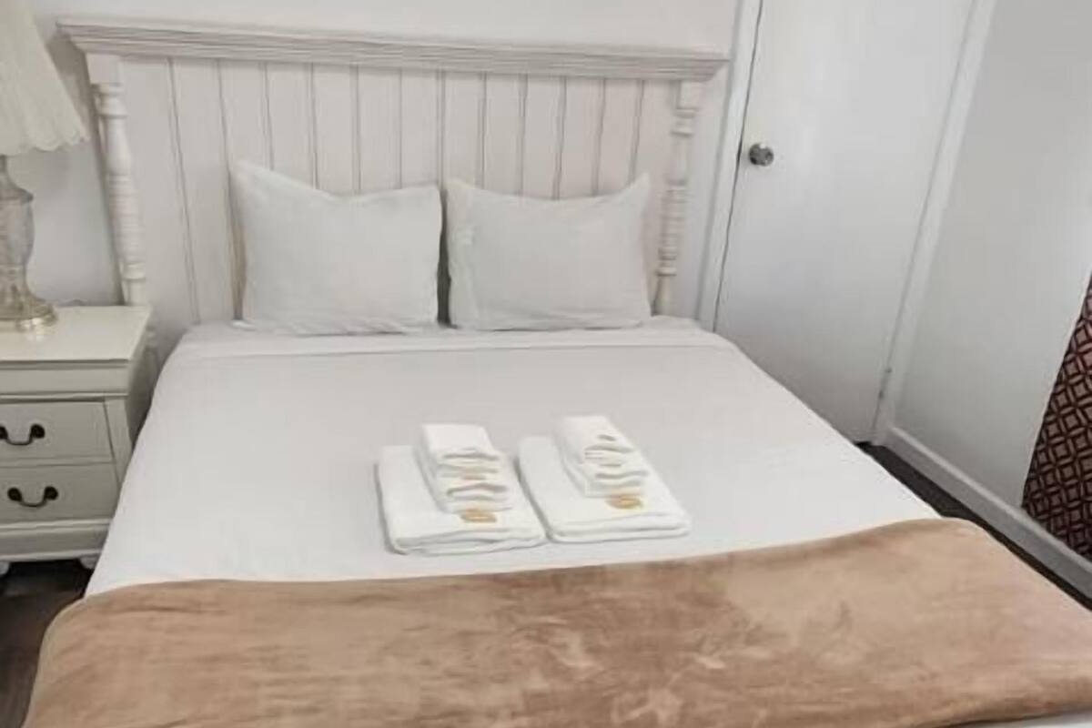 A neatly made bed with a brown throw blanket, white pillows, and a white headboard.