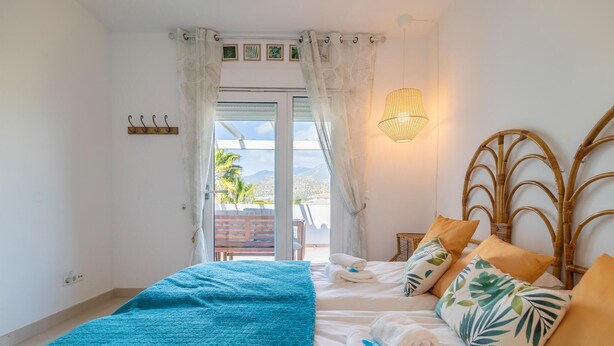 A bedroom with a bed, a nightstand, a lamp, and a view of the outdoors. - Luxurious home in Viñuela (Viñuela)