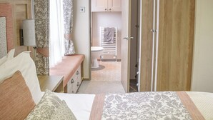 Een slaapkamer met een bed, nachtkastje en uitzicht op een badkamer met toilet en douche.