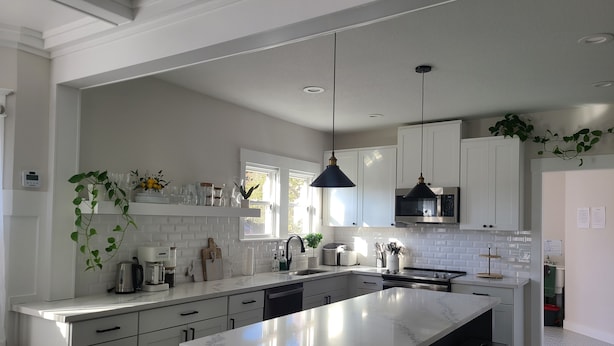 A modern kitchen with white cabinetry, a large island, and pendant lighting.