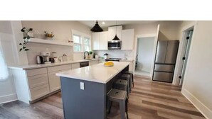 A modern kitchen with a central island, white cabinets, and stainless steel appliances.