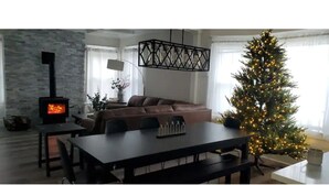 A cozy living room with a fireplace, a dining table, and a Christmas tree.