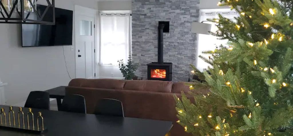 A living room with a fireplace, a dining table, and a Christmas tree.