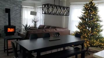 A cozy living room with a fireplace, a dining table, and a Christmas tree.
