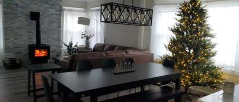 Een gezellige woonkamer met een open haard, een eettafel en een kerstboom.