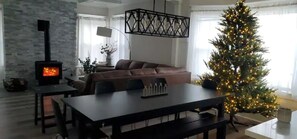Uma sala de estar aconchegante com lareira, uma mesa de jantar e um pinheiro de Natal.